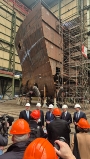 Der Bundespräsident, der Oberbürgermeister sowie die Chefs von Fassmer vor dem Segment für ein neues Schiff in der großen Schiffbauhalle
